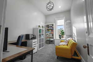 Carpeted home office featuring a chandelier