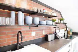 Kitchen view of open shelves, electric stove, backsplash, white cabinets, and light countertops