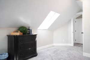 Additional living space with lofted ceiling, light carpet, and a skylight