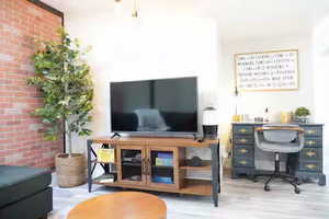 Home office featuring brick wall and wood finished floors
