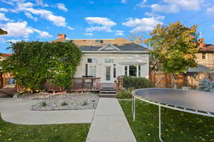 View of front of property featuring a trampoline, a wooden deck, stucco siding, a chimney, and a gate