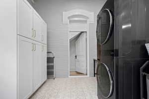 Laundry area featuring stacked washer / dryer and cabinet space