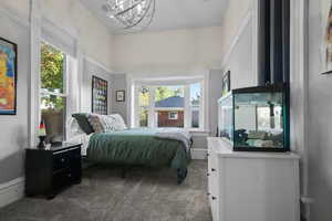 Bedroom with dark colored carpet and a chandelier