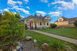 Victorian house featuring covered porch, a front yard, and a chimney
