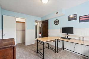 Office featuring light colored carpet, a textured ceiling, and a wainscoted wall