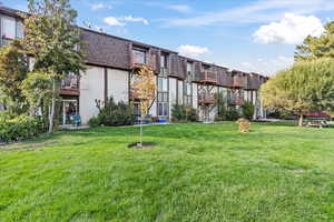 View of property's community featuring a lawn and a balcony
