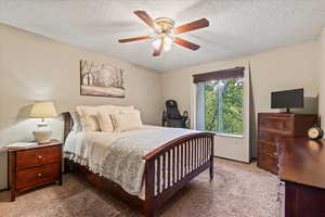 Bedroom featuring carpet flooring, ceiling fan, and a textured ceiling