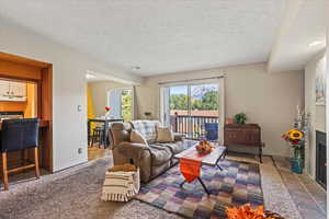 Carpeted living room featuring a fireplace and a textured ceiling