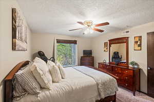 Bedroom featuring carpet floors, a textured ceiling, and ceiling fan