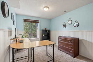 Carpeted office space with a textured ceiling and wainscoting