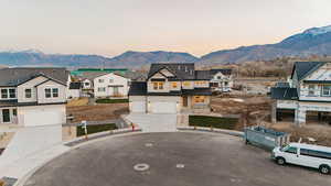 View of front of house featuring a mountain view, concrete driveway, board and batten siding, a residential view, and an attached garage