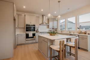 Kitchen with a kitchen breakfast bar, stainless steel appliances, light wood finished floors, backsplash, and a center island
