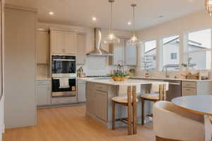 Kitchen featuring a kitchen bar, stainless steel appliances, a kitchen island, decorative backsplash, and light wood-style floors