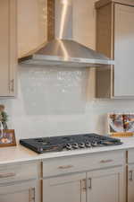 Kitchen with decorative backsplash, stainless steel gas cooktop, and light stone counters