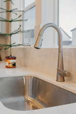 Kitchen view of a sink and tasteful backsplash