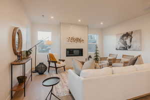 Living room featuring light wood-style flooring, a fireplace, and recessed lighting