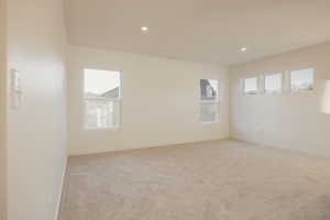 Empty room with light colored carpet, healthy amount of natural light, and recessed lighting
