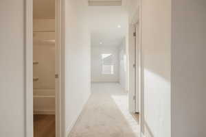 Corridor with light colored carpet and recessed lighting