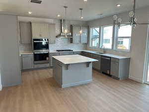Kitchen featuring gray cabinets, decorative backsplash, a kitchen bar, hanging light fixtures, and recessed lighting