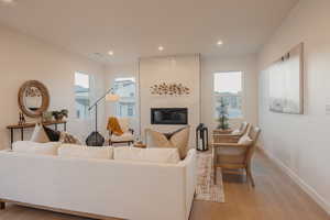 Living room featuring a large fireplace, light wood-style flooring, and recessed lighting