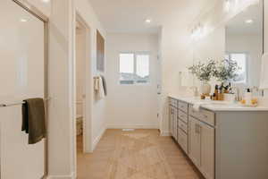 Bathroom with double vanity, a shower stall, light wood-style floors, and recessed lighting