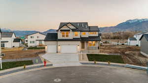 Modern farmhouse style home with a mountain view, covered porch, concrete driveway, board and batten siding, and roof with shingles