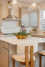 Kitchen featuring a breakfast bar, hanging light fixtures, backsplash, light stone countertops, and white cabinetry