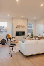 Living area with a fireplace, light wood-style flooring, and recessed lighting