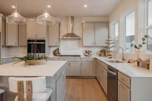 Kitchen with gray cabinets, a kitchen breakfast bar, light wood finished floors, stainless steel appliances, and decorative backsplash