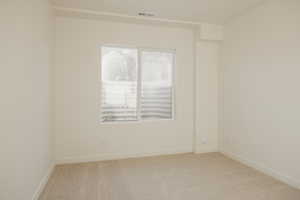Spare room featuring light carpet and baseboards