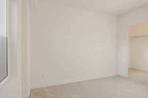 Unfurnished bedroom featuring a walk in closet and light colored carpet