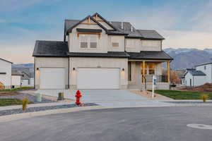 View of front of home with a porch, board and batten siding, a mountain view, roof with shingles, and concrete driveway