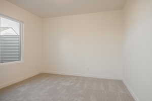 Unfurnished room featuring light carpet and baseboards