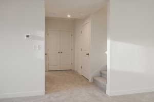 Corridor with baseboards and light colored carpet