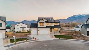 Modern farmhouse style home with a mountain view, driveway, covered porch, a shingled roof, and board and batten siding