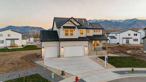 Modern farmhouse style home featuring board and batten siding, a mountain view, covered porch, concrete driveway, and a shingled roof