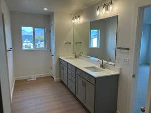 Bathroom featuring double vanity and light wood finished floors