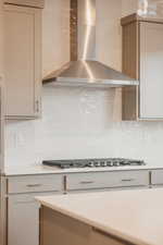 Kitchen with wall chimney exhaust hood, decorative backsplash, light stone countertops, and stainless steel gas stovetop