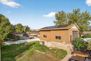 View of side of home featuring roof mounted solar panels, a fenced backyard, and a garage