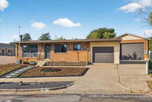 Ranch-style house featuring concrete driveway, brick siding, and an attached garage