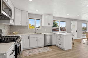 Kitchen with a peninsula, stainless steel appliances, a breakfast bar area, white cabinetry, and recessed lighting