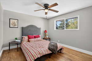 Bedroom with wood finished floors, a textured ceiling, and ceiling fan