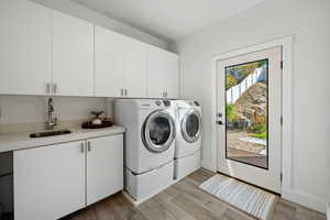 Washroom featuring light wood-style flooring, washer and dryer, and cabinet space