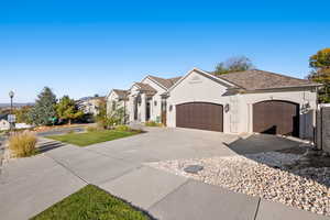 French provincial home with driveway, an attached garage, a front lawn, and stucco siding
