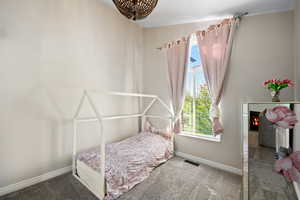 Carpeted bedroom with baseboards and a glass covered fireplace