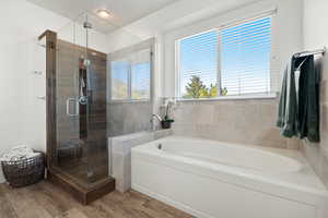 Full bath featuring a bath, wood finished floors, and a stall shower
