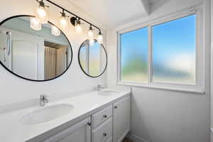 Full bath with double vanity and a shower with curtain