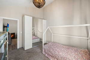Bedroom featuring dark colored carpet, a lit fireplace, and a closet