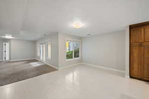 Spare room with a textured ceiling, light wood-style flooring, and light colored carpet