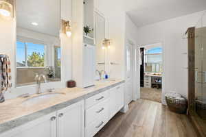 Bathroom with light wood-style floors, double vanity, and a stall shower
